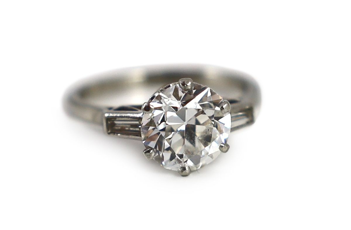 A mid 20th century platinum and single stone diamond ring, with trapeze cut diamond set shoulders